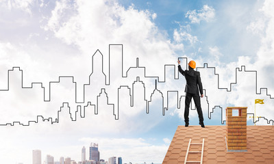Man architect draw silhouette of modern city on blue sky. Mixed media