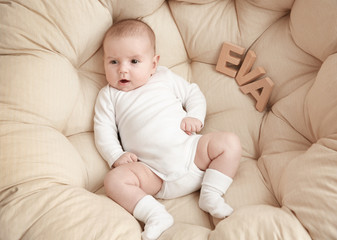 Cute baby with word EVA lying in armchair. Choosing name concept