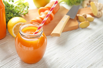 Jar of carrot juice on white wooden background