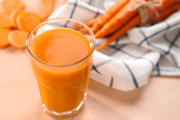Glass of carrot juice with slices on table