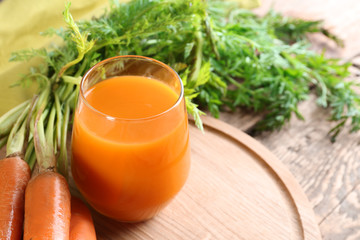 Glass of fresh carrot juice on wooden board