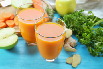 Glasses of fresh carrot juice on color wooden background