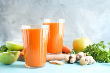 Glasses of fresh carrot juice on color background