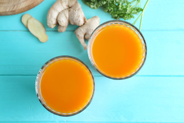 Glasses of fresh carrot juice on color wooden background