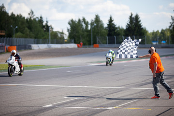 Man holding and waving the checkered flag at the finish of the race