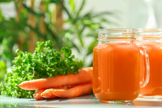 Mason jar of fresh carrot juice on table