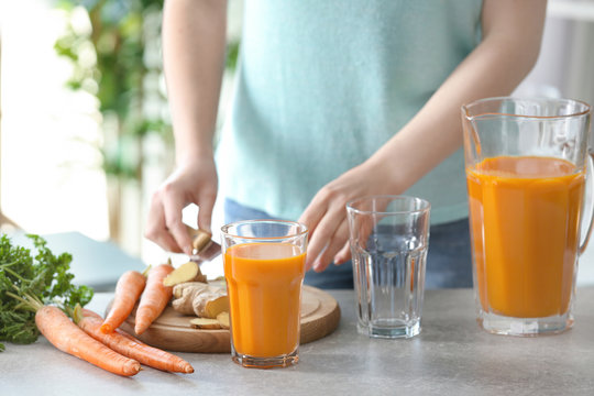 Young woman preparing fresh carrot juice in the kitchen