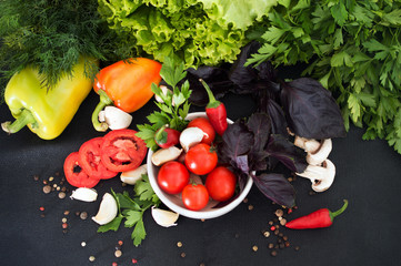 Fresh greens, spices and vegetables on a black background