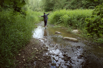 Woman in wild nature. Woman walking in stony stream in summer.
