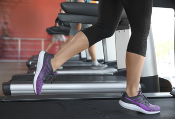 Fototapeta na wymiar Sporty young woman training legs on treadmill in gym, closeup