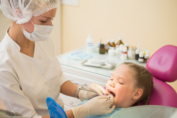 Obraz na płótnie Canvas Little cute girl sitting in chair at dentist clinic during dental checkup and treatment.