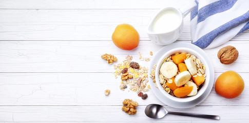 Breakfast, milk with muesli and fruit: apricots, banana and walnuts