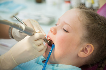 Little cute girl sitting in chair at dentist clinic during dental checkup and treatment, closeup portrait.