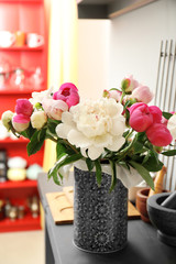 Vase with bouquet of beautiful peony flowers on table in room