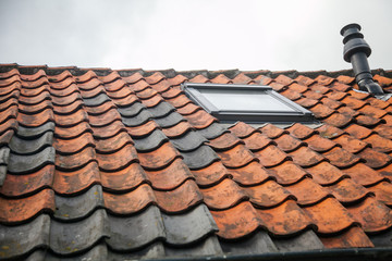 A window in the roof with red tiles and chimney