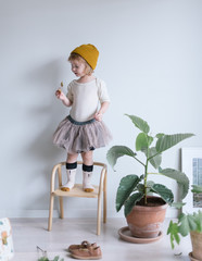 Kleines Mädchen im Tutu steht auf Stuhl in der Wohnung