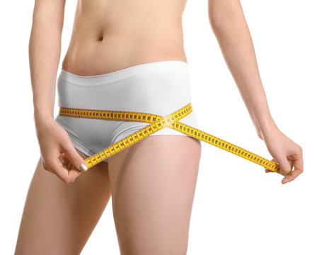 Beautiful young woman in underwear with measuring tape on white background, closeup. Diet concept