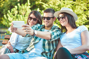 summer, holidays, vacation and happiness concept - group of friends taking picture with smartphone