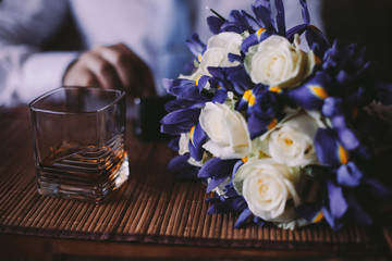 Wedding details groom's whiskey and bouquet on the table