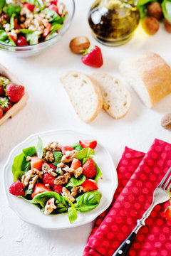 Fresh summer salad with strawberries, basil, walnuts with olive oil sauce and balsamic vinegar with white bread on a light background 