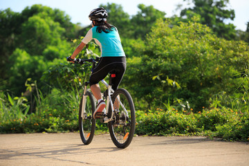 Naklejka premium woman cyclist cycling on summer forest trail
