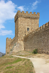 Fototapeta na wymiar An ancient tower and a wall with battlements, built of stones.