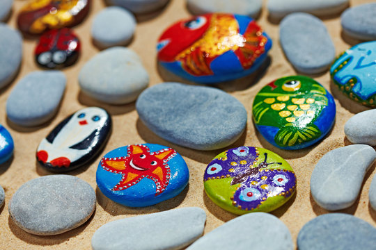 Rounded colorful stones pebbles shingle with pictures painted on them