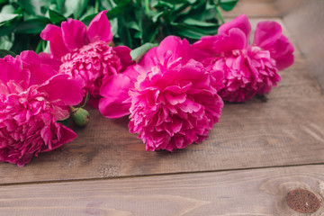 Row of peonies on wooden background with space for message. Women's or Mother's Day background. Top view