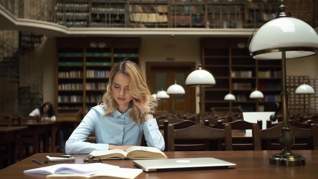 Student works with books and laptop in the library