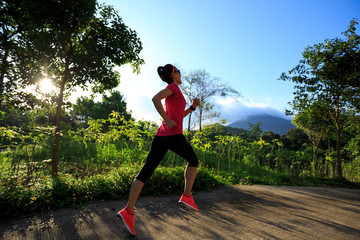 Young fitness woman running at forest trail