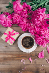 Obraz na płótnie Canvas A cup of coffee , pink peonies pattern and gift box on wooden background . Good morning. Women's or Mother's Day background.