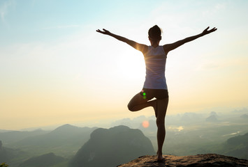 young fitness woman meditating on sunrise mountain peak