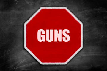 guns written on  a stop sign on a black chalkboard