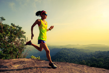 Young woman running on mountain top rock