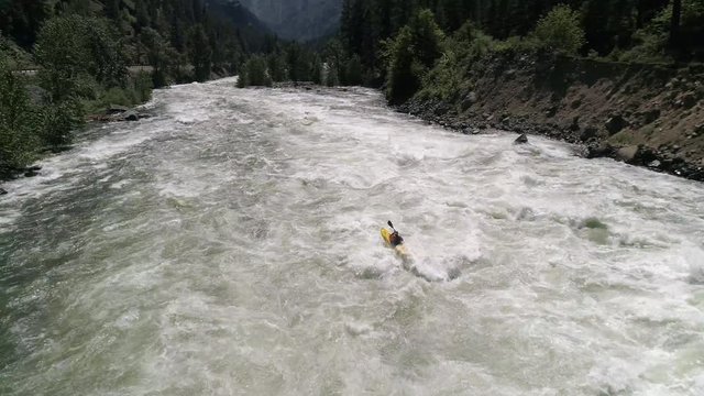 Slow Motion Drone Shot of Man Paddling Kayak in Waves of White Water Rapids