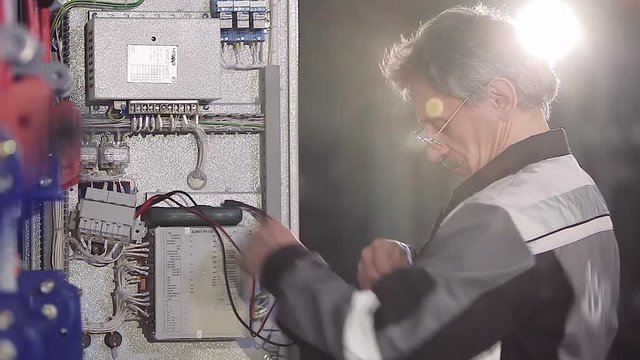 Close-up of experienced man working with electric meter.