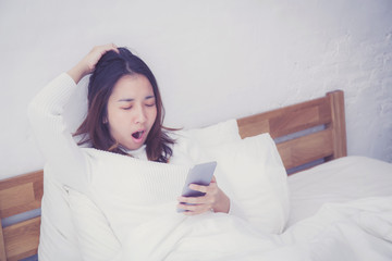 woman asian model holding a mobile phone with wake up in bedroom.