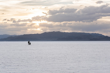 Two people in the distance in the vast salt flats near Salt Lake City, Utah during sunset