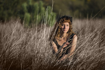 Young female in tall dry hay grass in black dress and ginger hair © Andriy Blokhin