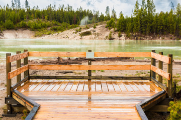 Green Sour lake in Yellowstone National Park with boardwalk sign and hot spring at Mud Volcano area