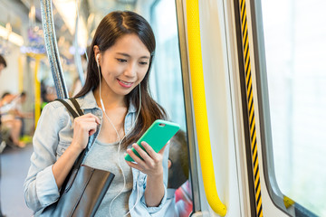 Woman listen to song on phone and taking the train in Hong Kong © leungchopan