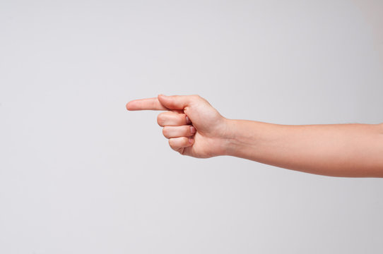 Female hand points a finger at something on white background.
