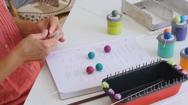 Artiest writes down her ideas for matching bead colors togeather on paper in her studio