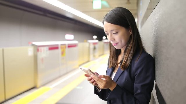 Businesswoman using cellphone at Tokyo subway