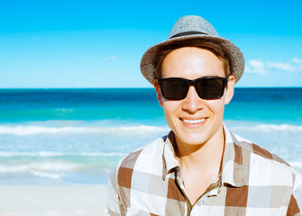 Portrait of happy young handsome man standing on the beach.  