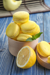 Box with tasty lemon macarons on wooden table, closeup