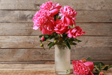 Vase with beautiful peonies on wooden background