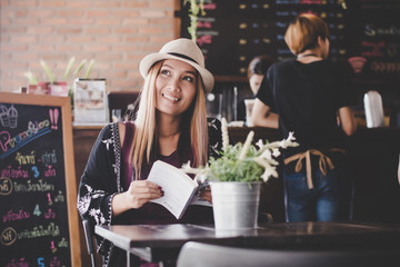 Happy business woman reading book while relaxing at cafe.