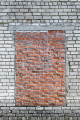 In the brick wall of white brick capped with red brick window.