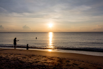 Fototapeta na wymiar Father, mother, and child Enjoy the sea at dawn.